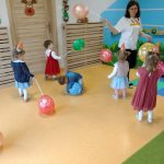 Grupa dzieci z opiekunką bawiąca się kolorowymi balonikami