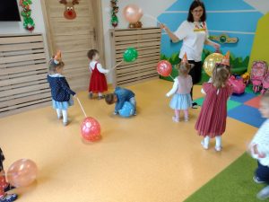 Grupa dzieci z opiekunką bawiąca się kolorowymi balonikami