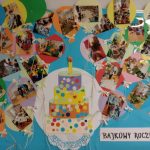 Gazetka ścienna przedstawiająca tort z papieru kolorowego, wokół tortu zdjęcia dzieci podczas zabaw i zajęć w żłobku
