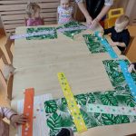 Dzieci siedzą przy stoliku i robią pracę plastyczną z papieru: zimowy szalik