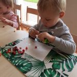 Chłopiec wykleja pracę plastyczną z kolorowych kulek zrobionych z bibuły