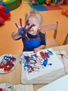 Dziewczynka pokazuje otwartą dłoń pomalowaną farbą