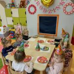 Dzieci siedzą przy stole i częstują się urodzinowymi babeczkami