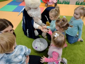 Dzieci wraz z postacią obraną w długi czarny płaszcz oglądają kostki lodu