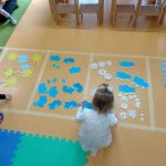 Dzieci układają symbole zjawisk atmosferycznych na wyznaczonych kwadratach na podłodze.