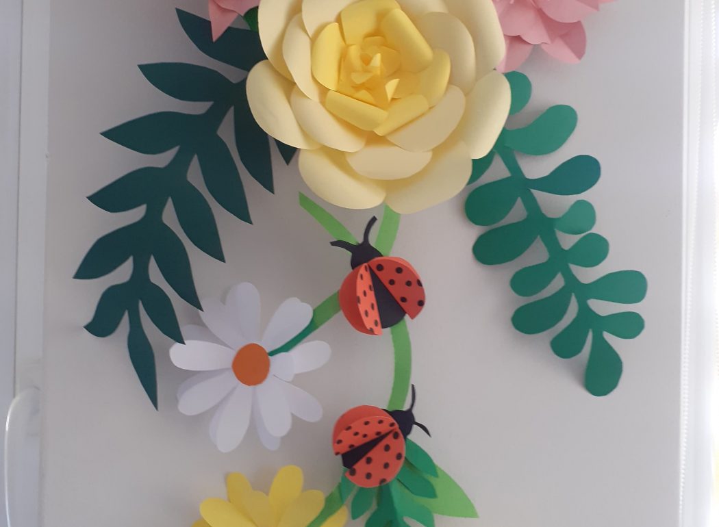 Dekoracja ścienna w formie kolorowych kwiatów wykonanych z papieru.