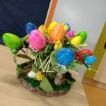 Praca plastyczna w formie stroika. Kolorowe jajka nabite na patyczek wyglądają jak kwiaty. Całość przedstawia się jak bukiet świąteczny.