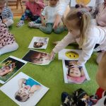 Dzieci oglądają rozłożone na dywanie fotografię związane z emocjami.