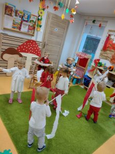 Dzieci ubrane na biało - czerwono, trzymają w dłoniach tasiemki w kolorach polskiej flagi i wymachują nimi do piosenki.