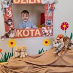 Chłopiec stoi i pozuje do zdjęcia w ramce z napisem "Dzień Kota".