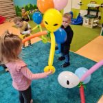 Dzieci tańczą trzymając w dłoniach balony z których zrobione są "kosmoludki".