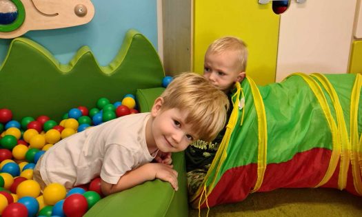 Dwóch chłopców bawi się w basenie z kolorowymi piłeczkami.