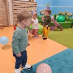 Dzieci tańczą na sali zabaw. Na podłodze leżą kolorowe baloniki.