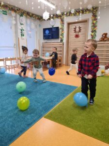Dzieci tańczą z kolorowymi balonikami na sali zabaw.