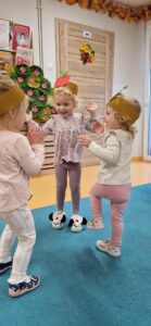 Dziewczynki ubrane w opaski z jabłuszkiem i gruszką tańczą do piosenki o owocach.