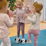 Dziewczynki ubrane w opaski z jabłuszkiem i gruszką tańczą do piosenki o owocach.